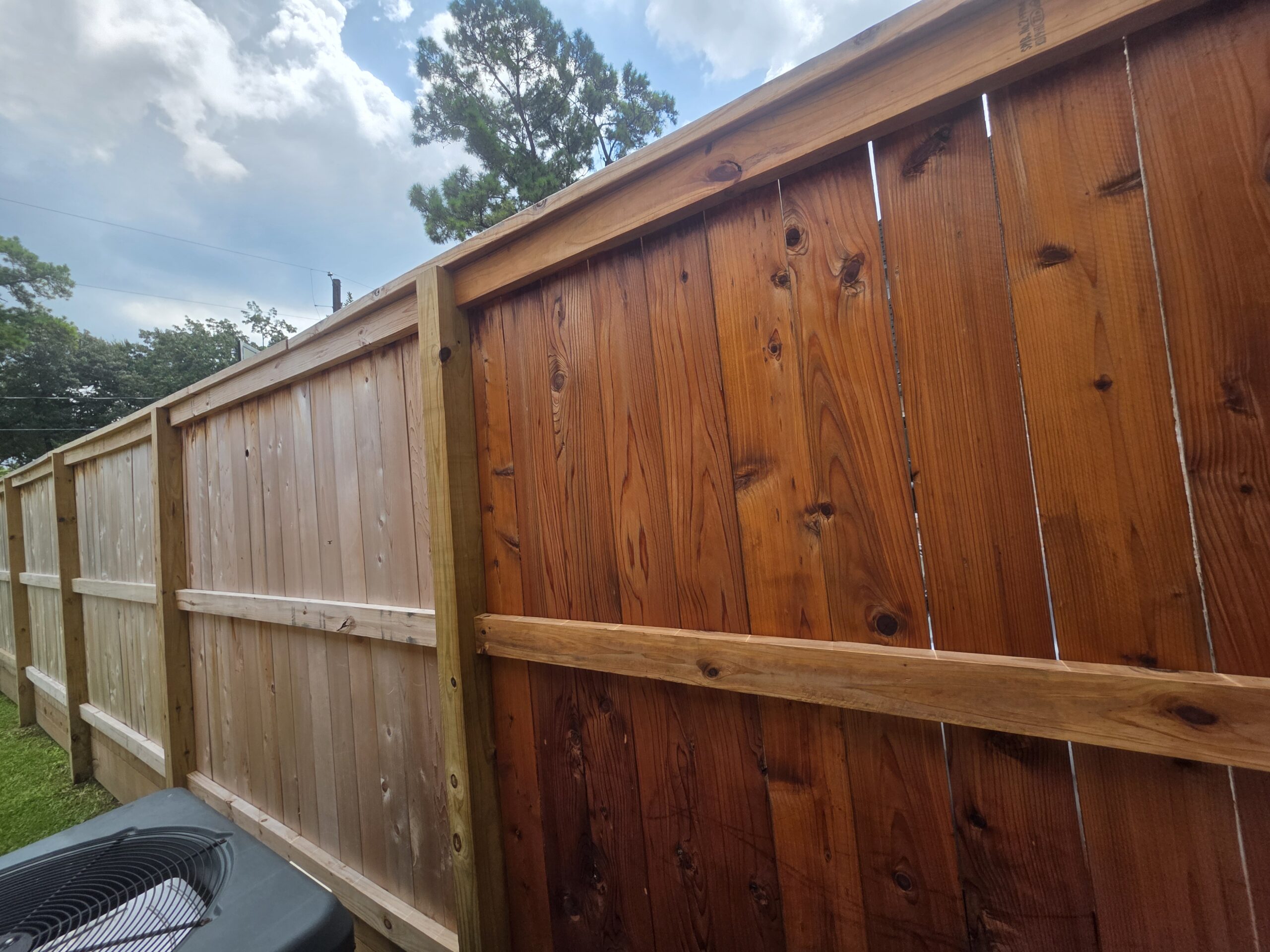 Restored wooden privacy fence with a refreshed natural wood appearance.